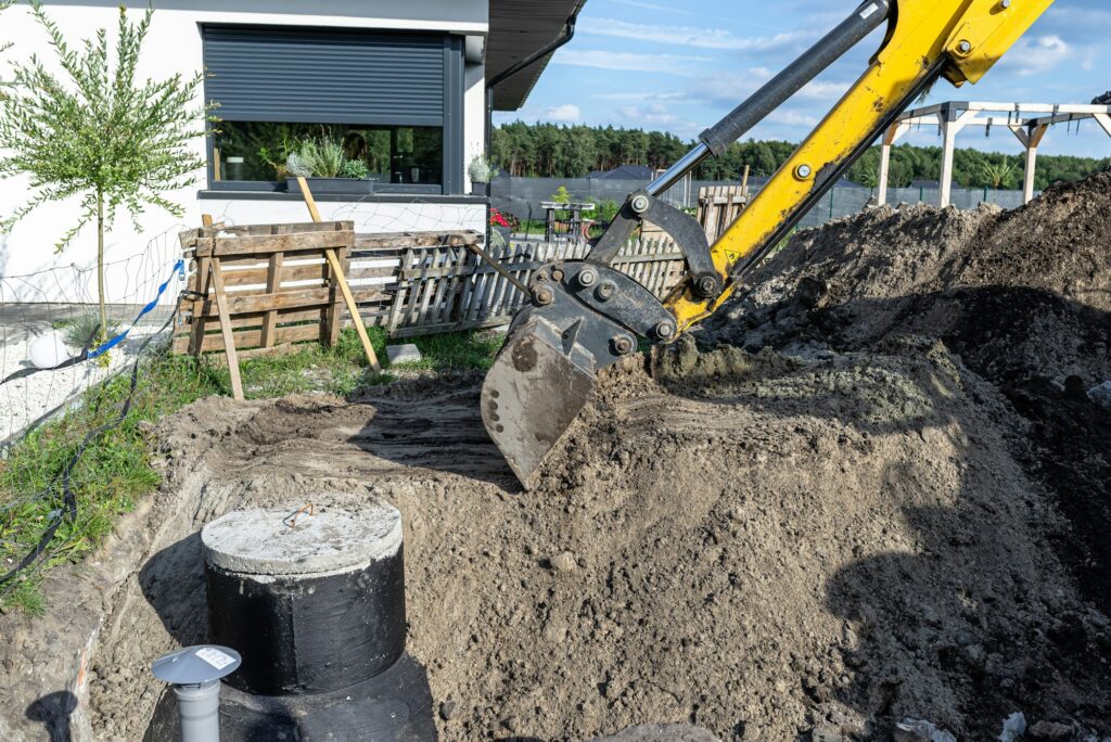 Using an excavator to bury a 10 m3 concrete septic tank located in the garden next to the house.